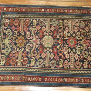 K&ouml;nnte beinhalten: Ein antiker t&uuml;rkischer Teppich mit dunkelblauem Hintergrund und komplizierten geometrischen Mustern in Rot-, Beige- und Cremet&ouml;nen. Der Teppich hat einen Rand mit einem sich wiederholenden Muster aus Sternen und Blumen.