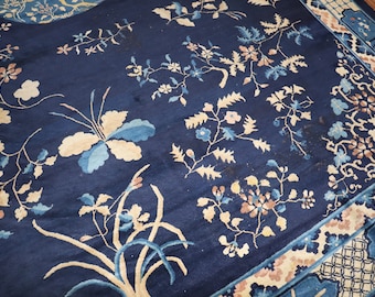 May include: A blue rug with a floral pattern in shades of cream, pink, and blue. The rug has a border with a geometric design.