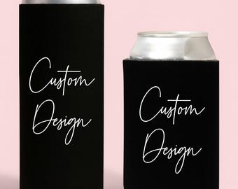 May include: Two black can coolers with the words "Custom Design" in white script. One cooler is tall, the other is short. Both are on a pink background.