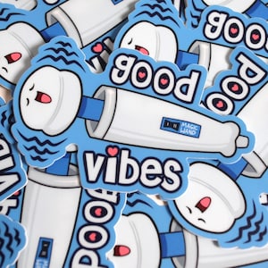 May include: A collection of blue stickers with a cartoon design. Each sticker features a white tube with a smiling face and the words "good vibes" in white. The stickers also have the text "Magic Wand".