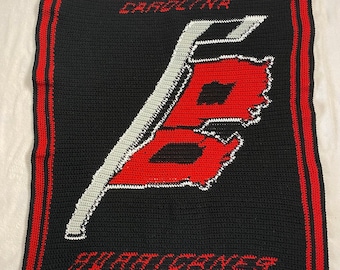 May include: Crocheted blanket with a red and white outline of the state of North Carolina and the text "Carolina" and "Tar Heels" in white.