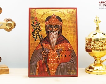 May include: Hand-painted icon of Saint Basil the Great, a Byzantine Orthodox saint, with a gold background and red border. The icon depicts Saint Basil holding a staff and a vessel, with a crown on his head. The text "Άγιος Βασίλειος" is written in Greek at the top of the icon.