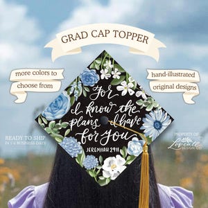 May include: A black graduation cap topper with a floral design in blue and white, featuring the quote "For I know the plans I have for you" from Jeremiah 29:11. The topper has a gold tassel and is hand-illustrated.