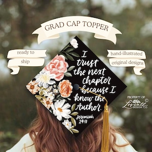 Op de afbeelding: Een zwarte afstudeerhoedtopper met perzik-, witte en groene bloemmotieven. De tekst luidt "Ik vertrouw op het volgende hoofdstuk omdat ik de Auteur ken" met de verwijzing Jeremia 29:11. Een gouden kwast is bevestigd.