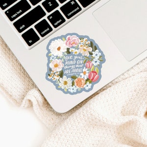 May include: A blue and white floral sticker with the text "Set your mind on things that are above" and the scripture reference "Colossians 3:2".