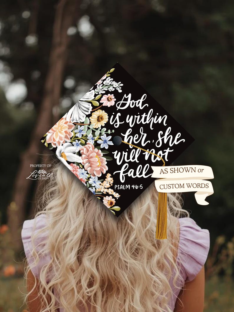 A person with long, curly blonde hair wearing a purple top, with a graduation cap decorated with a floral design and text.