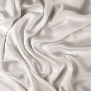 May include: A close-up of smooth, white satin fabric with soft, flowing folds and wrinkles.