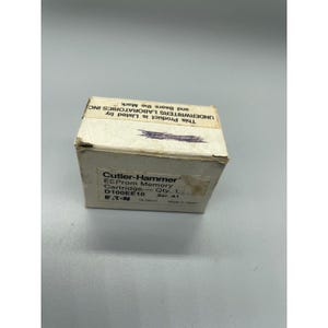 Könnte beinhalten: Ein kleiner, cremefarbener Karton mit Text, darunter "Cutler-Hammer" und "EEProm Memory Cartridge". Die Box trägt auch den Text "UNDERWRITERS LABORATORIES INC." und "D100EE10". Die Box ist leicht abgenutzt.