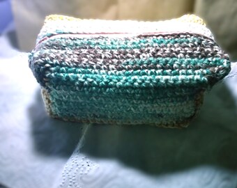 May include: A handmade crochet basket in shades of teal, brown, white, and tan. The rectangular basket has a textured appearance, with visible stitches. The edges are neatly finished, showcasing the craftsmanship of the piece.