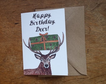 Happy Birthday Deer! Greeting Card. A Birthday stag carrying a birthday present in woodland colours in his antlers by Alice Draws The Line