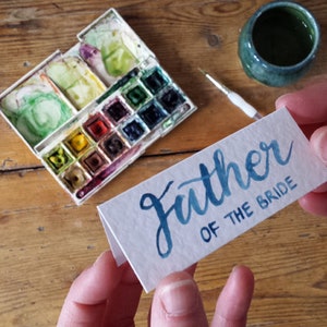 Aquarel borstel belettering plaats naamkaartjes voor bruiloften, door Alice Draws The Line, uw keuze van kleuren op een wit gehamerd textuur kaart