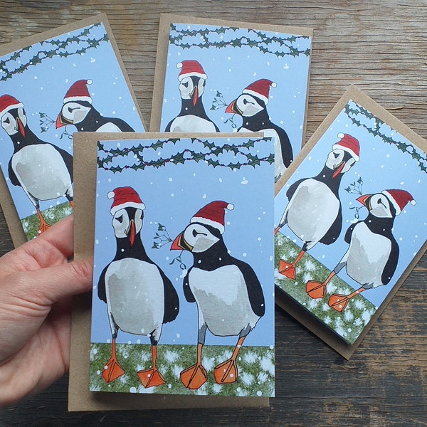 Puffin Christmas Cards con illustrazioni di Alice Disegna la linea; con pulcinelle di mare che indossano cappelli di Natale. Disponibile singolarmente o in confezione da 4