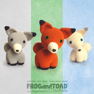 May include: Three crocheted fox figurines in gray, orange, and cream colors. Each fox has a white muzzle, black-tipped ears, and button eyes. The orange fox is in the center, flanked by the gray and cream foxes. The background is divided into three vertical sections.