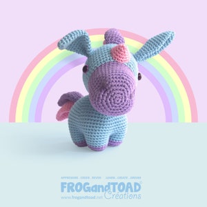 May include: A handmade crochet unicorn toy in blue, purple, and pink, set against a rainbow backdrop. The unicorn features large ears, a horn, and wings. The text "FROGandTOAD" is visible at the bottom of the image.