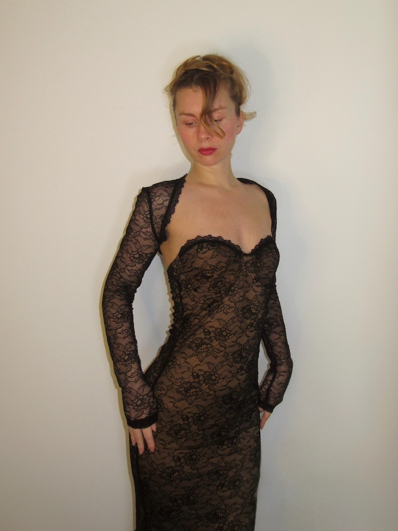 May include: A black lace dress with long sleeves. The dress has a sweetheart neckline and a fitted silhouette. The lace pattern is intricate and covers the entire dress. The dress is a formal wear item.