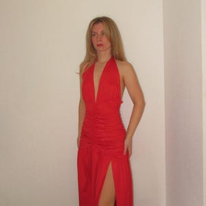 Może przedstawiać: Czerwona sukienka maxi w stylu halter z rozcięciem z przodu i marszczonym gorsetem.