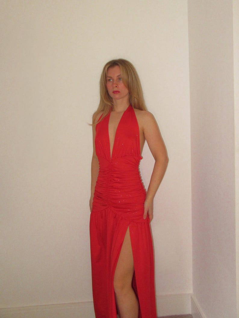 Może przedstawiać: Czerwona sukienka maxi w stylu halter z rozcięciem z przodu i marszczonym gorsetem.