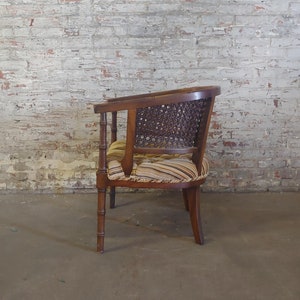May include: A brown wooden chair with a woven cane back and a striped fabric seat. The chair has a curved back and four legs.