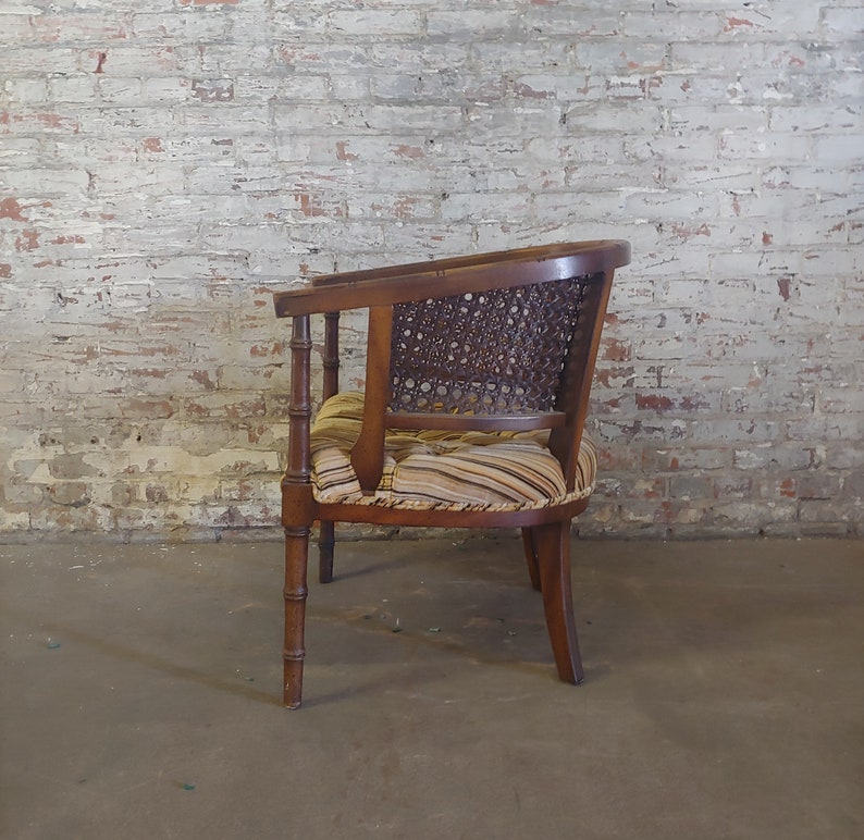 May include: A brown wooden chair with a woven cane back and a striped fabric seat. The chair has a curved back and four legs.