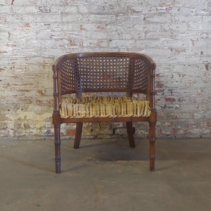 May include: A brown wicker and wood armchair with a striped fabric seat cushion. The chair has a woven back and a simple, elegant design.
