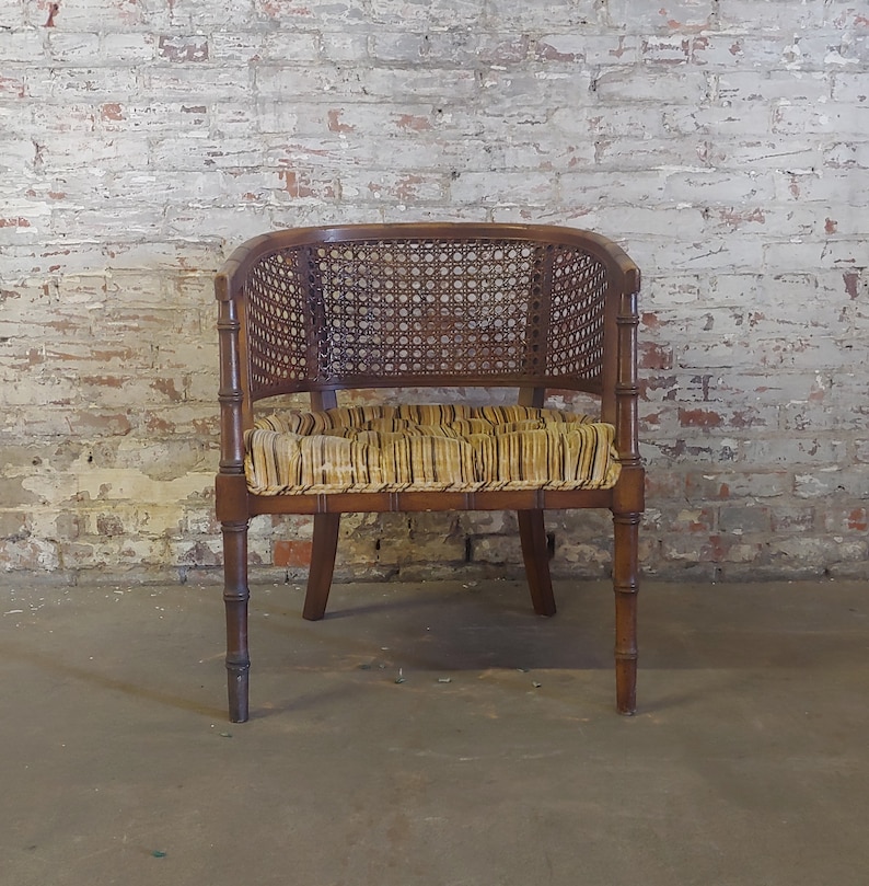 May include: A brown wicker and wood armchair with a striped fabric seat cushion. The chair has a woven back and a simple, elegant design.