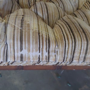 May include: Close-up of a brown and white striped fabric with tufted buttons. The fabric is likely upholstery for a sofa or chair.