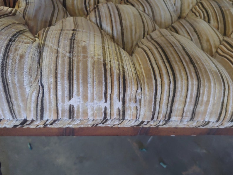 May include: Close-up of a brown and white striped fabric with tufted buttons. The fabric is likely upholstery for a sofa or chair.