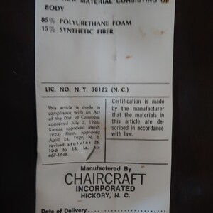 May include: A white tag with black text stating "Under Penalty of Law This Tag Not To Be Removed Except By The Consumer" and "All New Material Consisting of Body 85% Polyurethane Foam 15% Synthetic Fiber". The tag also includes the text "Lic. No. N.Y. 38182 (N.C.)" and "Manufactured By CHAIRCRAFT INCORPORATED HICKORY, N.C.". The tag has a handwritten number "7" and the text "M-1379*" at the bottom.