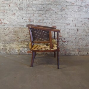 May include: A wooden armchair with a woven cane back and a striped fabric seat. The chair has a dark wood finish and is in good condition.