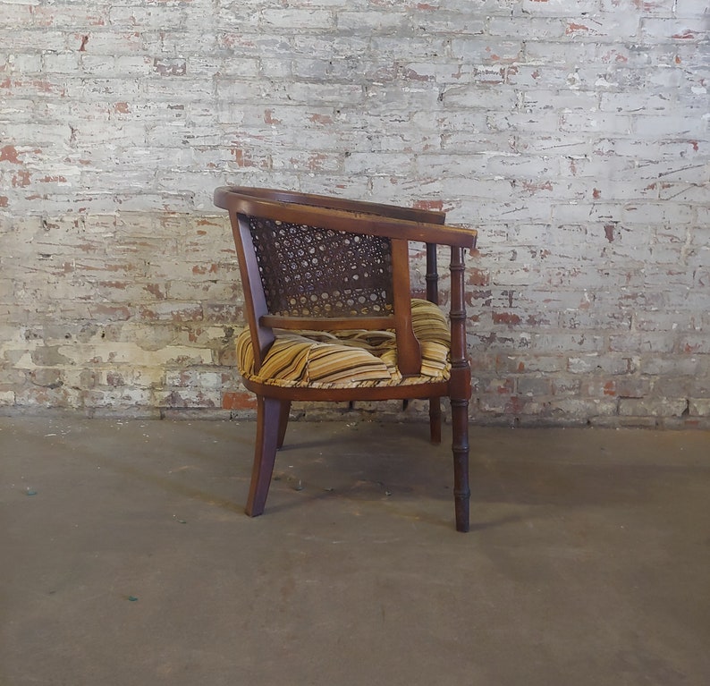 May include: A wooden armchair with a woven cane back and a striped fabric seat. The chair has a dark wood finish and is in good condition.