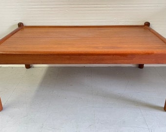 May include: A rectangular wooden coffee table with a light brown finish and a simple design. The table has four legs and a flat top.