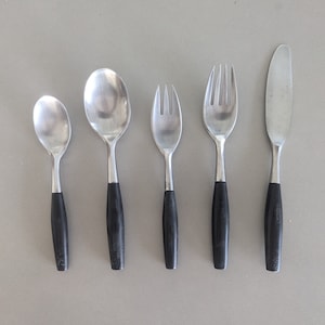 May include: A set of five silver-toned flatware pieces with black handles. The set includes a knife, two forks, and two spoons.