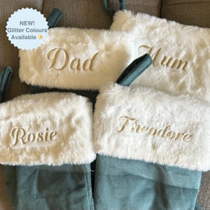 Może przedstawiać: Cztery zielone świąteczne skarpety z aksamitu z białym sztucznym futerkiem. Skarpety są spersonalizowane z imionami "Dad", "Mum", "Rosie" i "Theodore" złotymi literami.