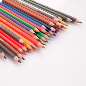 May include: A set of colored pencils with a variety of colors, including red, orange, yellow, green, blue, purple, and brown. The pencils are arranged in a fan shape, with the tips of the pencils pointing towards the right side of the image. The pencils are all sharpened and ready to use.