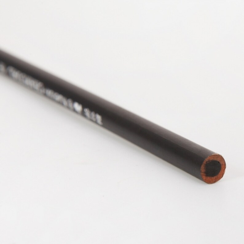 May include: A black pencil with a sharpened point. The pencil is made of wood and has a black finish.