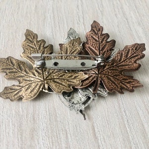 Peut inclure: Une broche en forme de trois feuilles d'&eacute;rable, tonifi&eacute;e or, argent et cuivre.