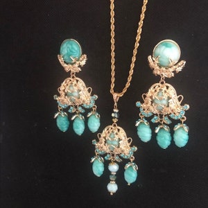 Könnte beinhalten: Ein goldenes Halsketten- und Ohrring-Set mit türkisfarbenen und klaren Glasperlen. Die Halskette und die Ohrringe haben ein filigranes Design.