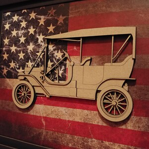May include: A brown wooden cutout of a vintage car with a black and red American flag background.