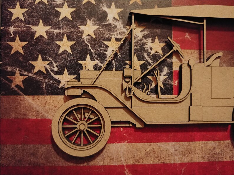 May include: A brown cardboard model of a vintage car, with a steering wheel and a detailed interior, is set against a backdrop of an American flag.