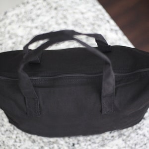 May include: A black canvas tote bag with two handles and a zipper closure.