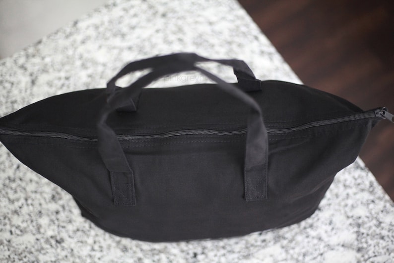 May include: A black canvas tote bag with two handles and a zipper closure.