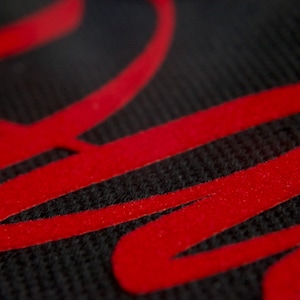 May include: Close-up of a black fabric with a red, stylized word "Raw" printed on it.