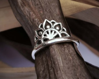 Könnte beinhalten: Ein silberner Ring mit einem detaillierten Mandala-Design. Der Ring liegt auf einem Stück Holz.