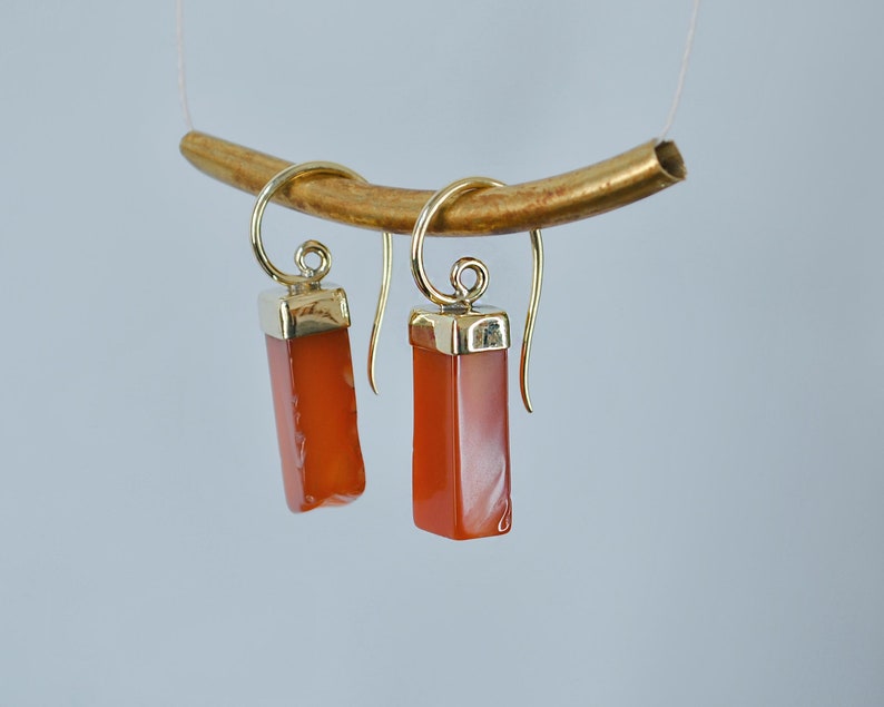 Puede incluir: Un par de pendientes de oro con piedras rectangulares de cornalina naranja.