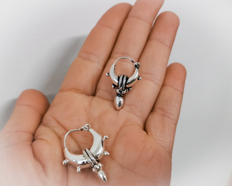 Peut inclure: Une paire de boucles d'oreilles cr&eacute;oles en argent avec un motif de croissant de lune et une forme de larme pendante.