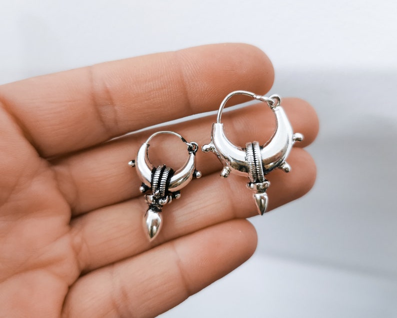 Peut inclure: Deux boucles d'oreilles cr&eacute;oles en argent avec un design pointu. Les boucles d'oreilles ont une surface textur&eacute;e et une petite perle ronde au bas.