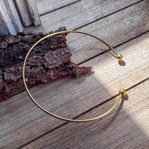 May include: A gold-toned metal choker necklace with two round ball accents.