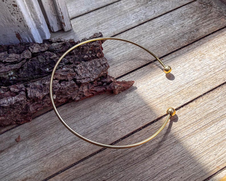 May include: A gold-toned metal choker necklace with two round ball accents.