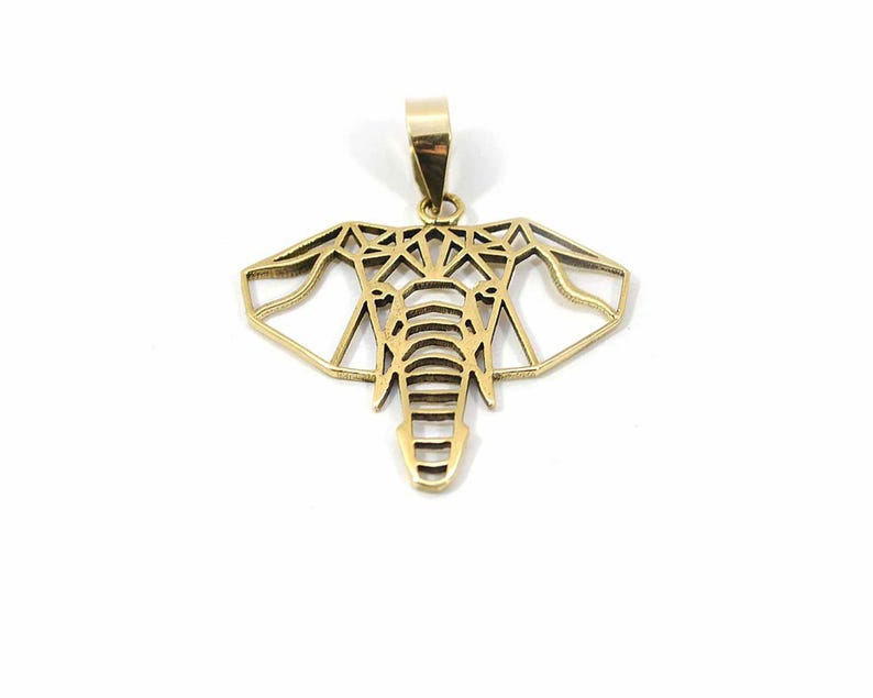 May include: A gold-coloured elephant head pendant. The pendant has a geometric design and a loop at the top for a chain. The elephant's head is detailed with lines and shapes, creating a modern and stylish appearance. The pendant is suitable for a necklace.