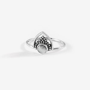 May include: A silver ring with a white stone set in a geometric design.